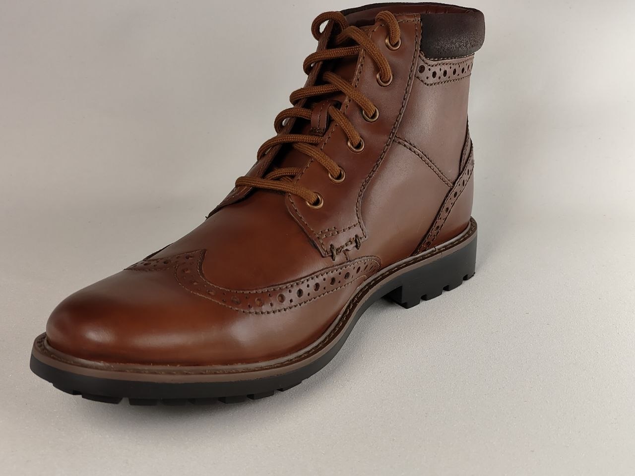 Brown leather boot with laces on a light gray background