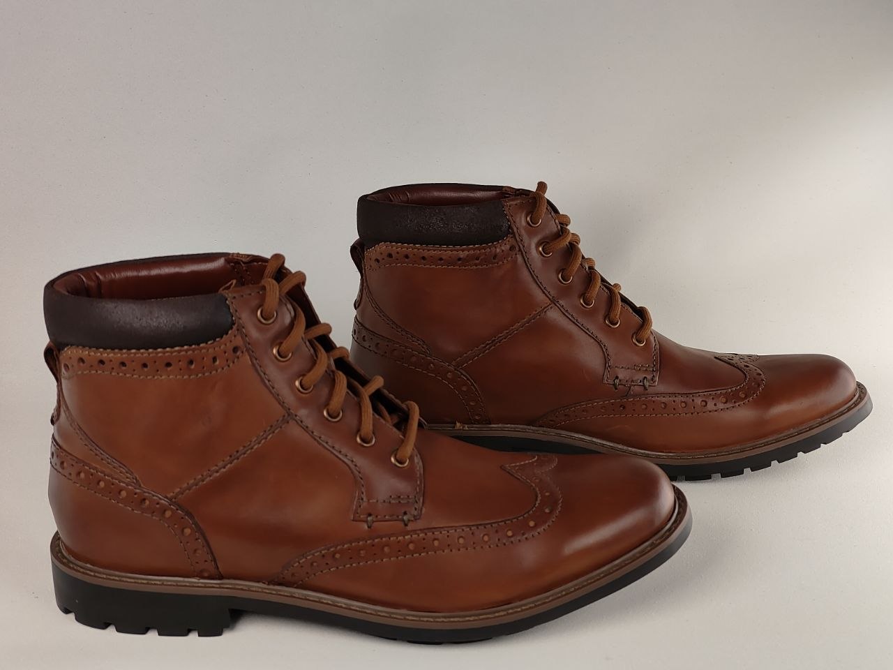 Pair of brown leather boots on a light gray background
