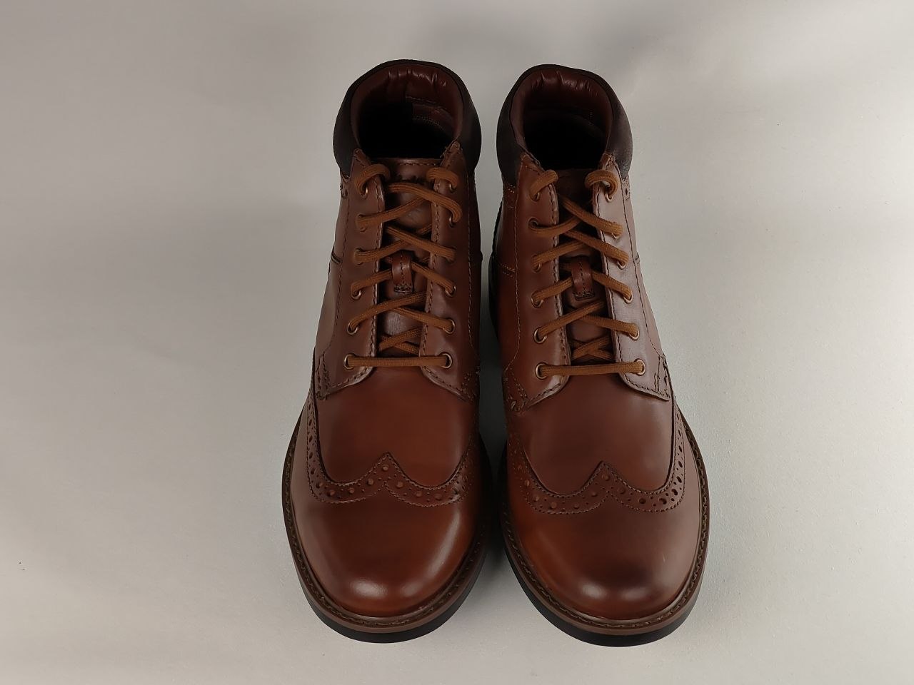 Pair of brown leather boots on a light gray background