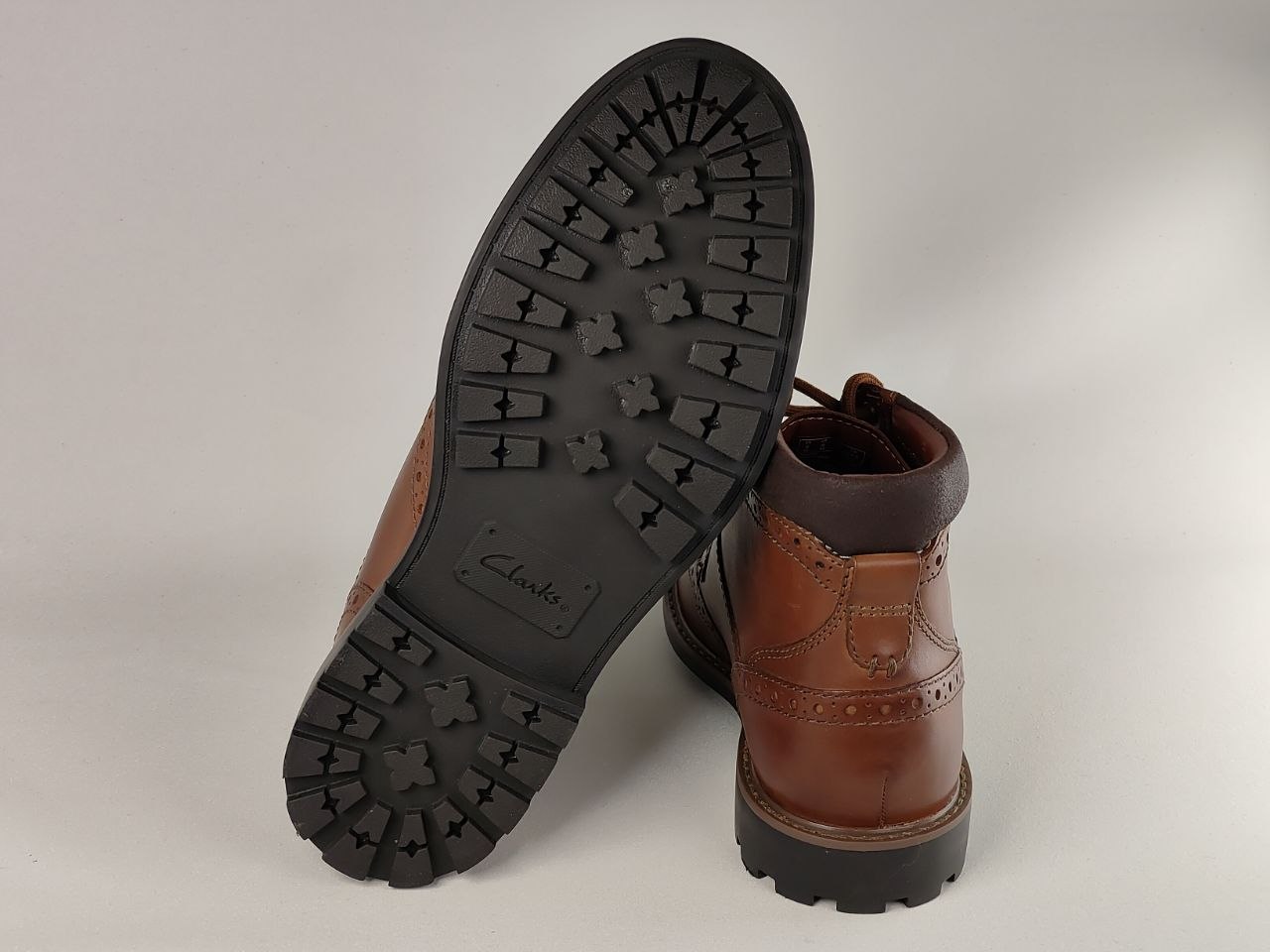 Brown leather boot with black sole on a light gray background