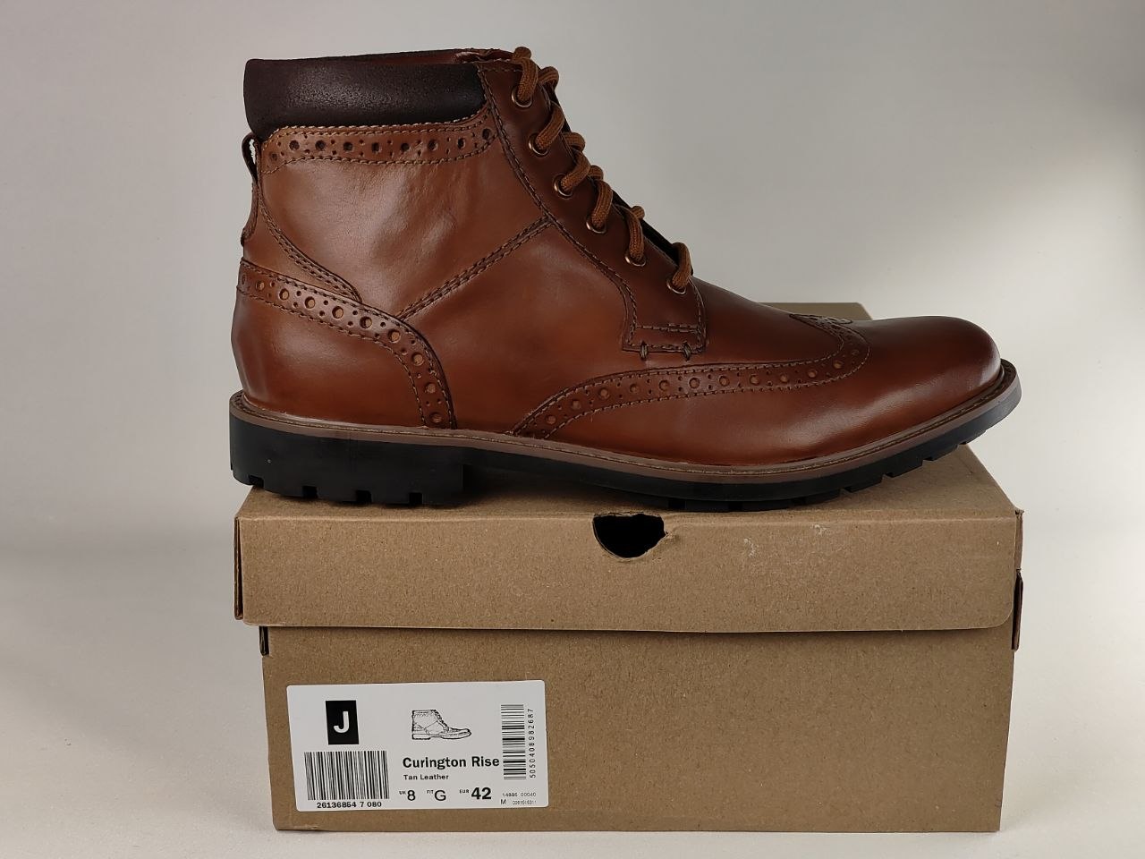 Brown leather boot on a cardboard box with a visible brand label.
