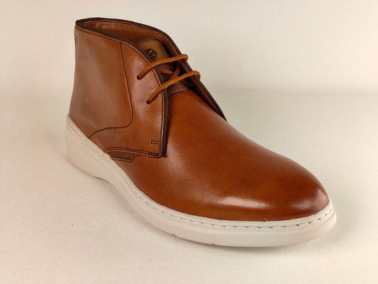 Brown leather chukka boot with white sole on a beige background