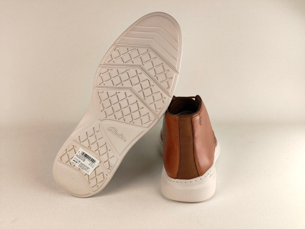 Brown leather shoe with white sole on a beige background