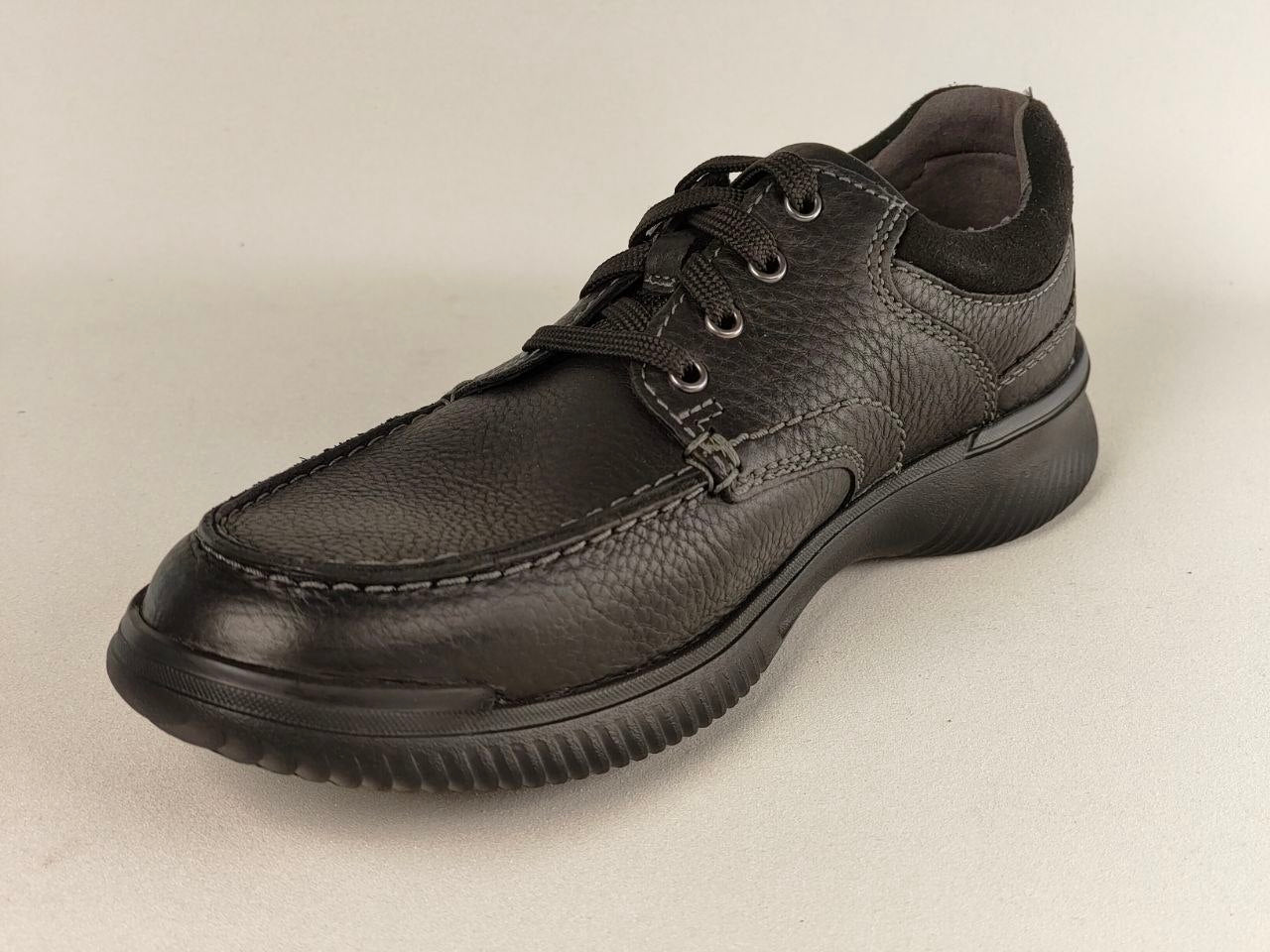 Black leather shoe on a beige background