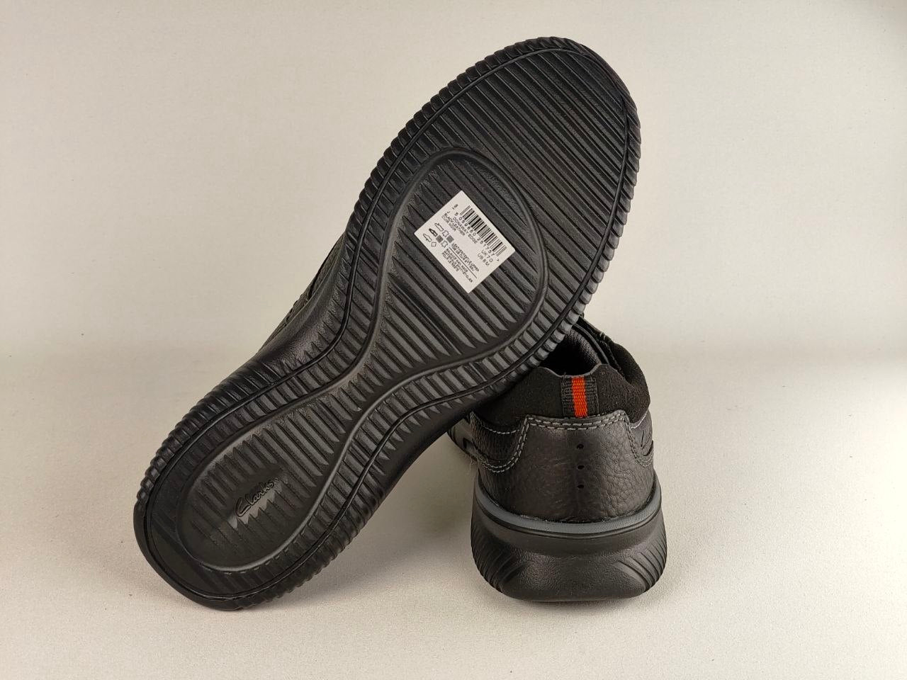 Black shoes with a focus on the sole and brand label on a light gray background