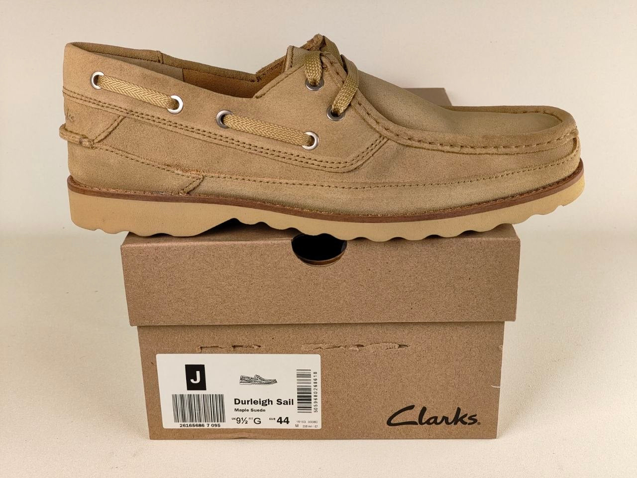 Brown Clarks shoe on top of a matching box against a beige background
