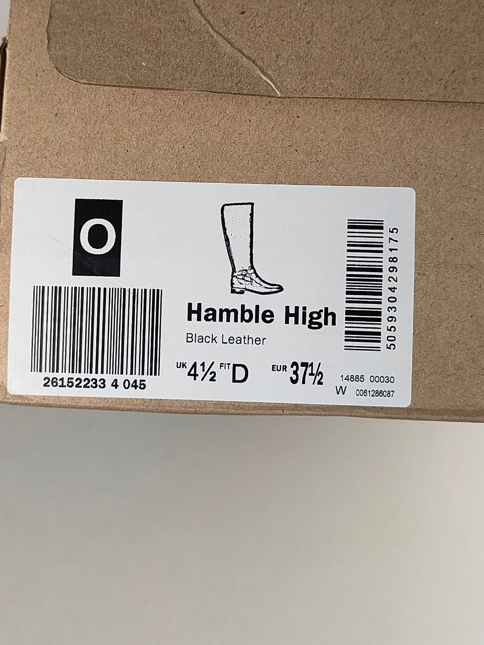 A close-up of a cardboard shoe box with a white product label reading 'Hamble High' and 'Black Leather,' including a boot silhouette, barcode, and size information.
