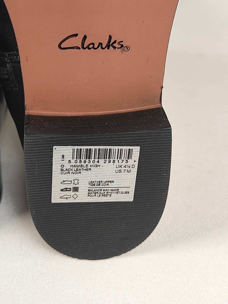 Close-up of the underside of a Clarks shoe showing the tan insole with the black Clarks logo and a white size/material label on the black outsole.