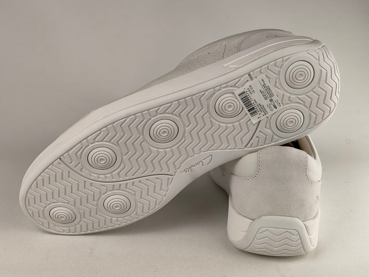 Close-up of a white sneaker sole with tread pattern on a gray background