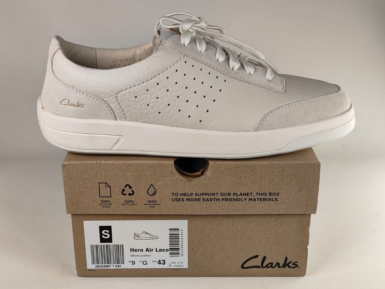 Light gray sneaker on a Clarks shoe box with a beige background