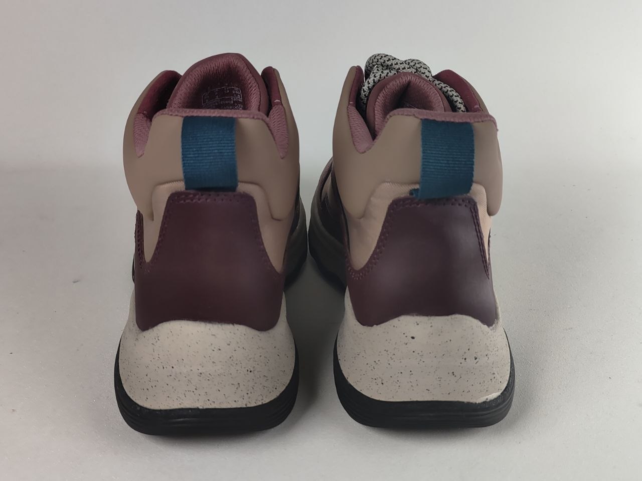 A pair of high-top sneakers shown from the back, featuring dusty pink and burgundy panels, a teal pull tab, and a speckled off-white midsole.