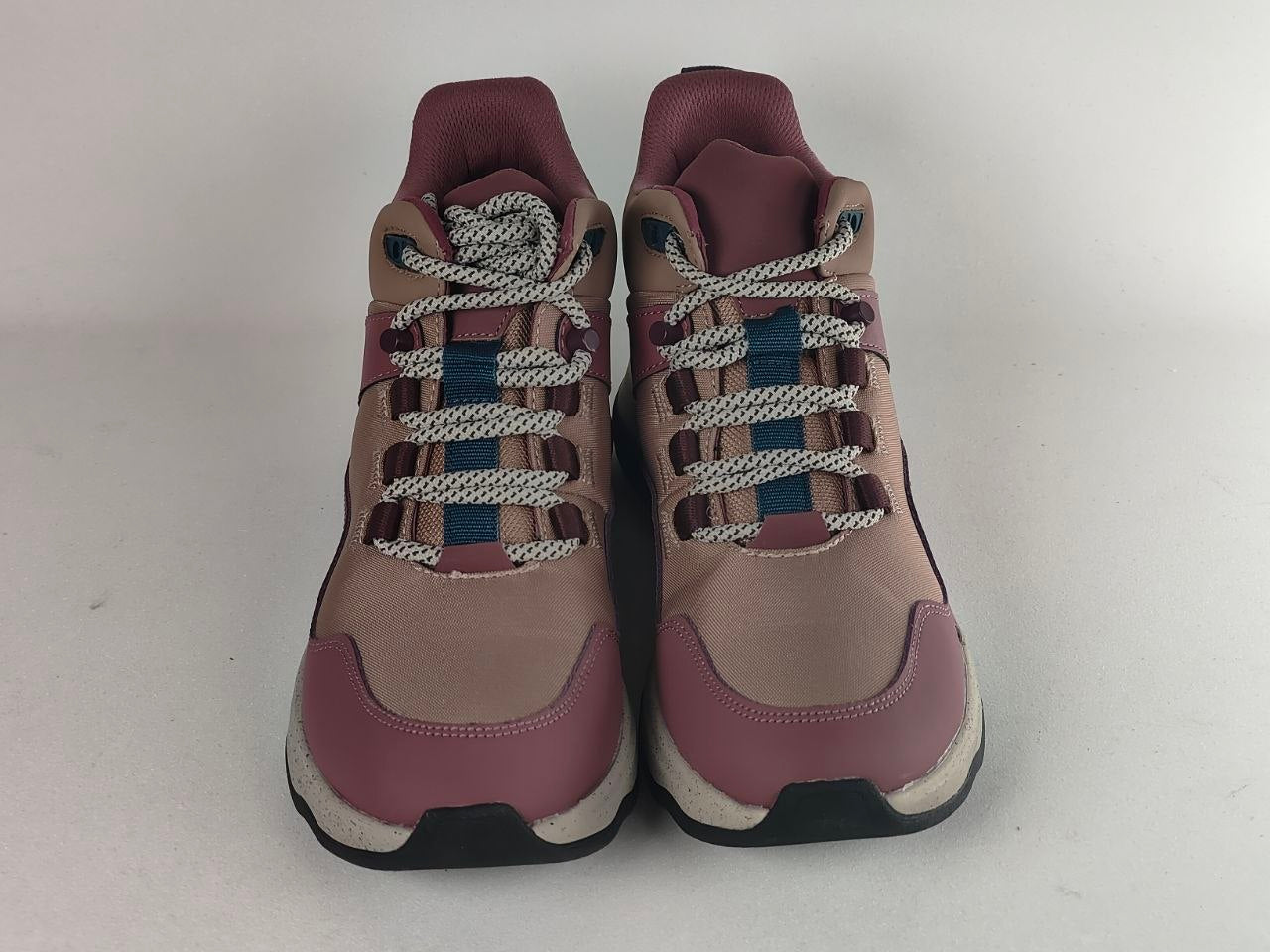 A pair of women's mid-top sneakers in dusty rose and beige, featuring multi-colored laces with white, blue, and dark red sections, photographed against a plain light gray background.