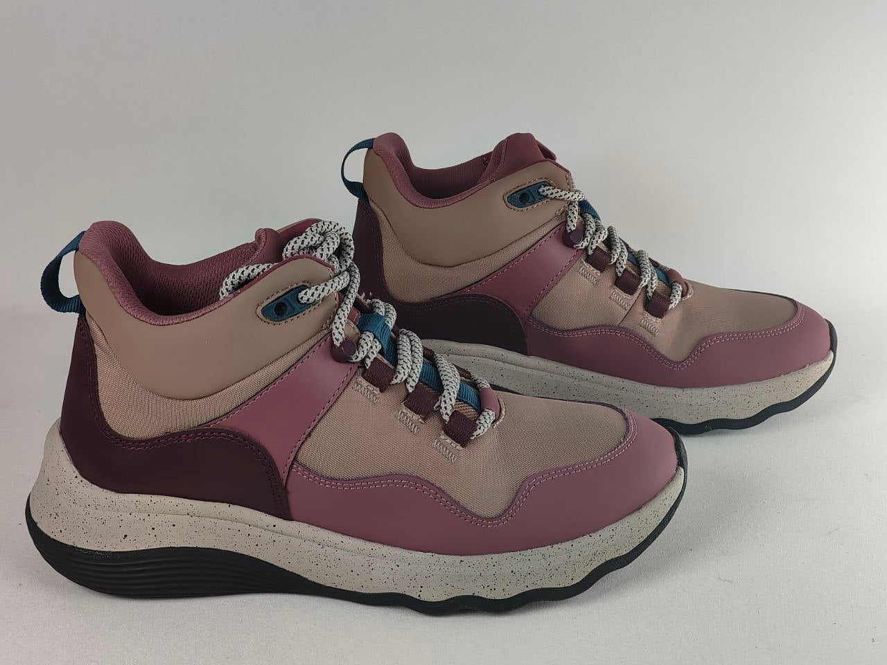 A pair of mid-top athletic sneakers in dusty rose, mauve, and beige, featuring chunky speckled white midsoles and white laces with blue accents.