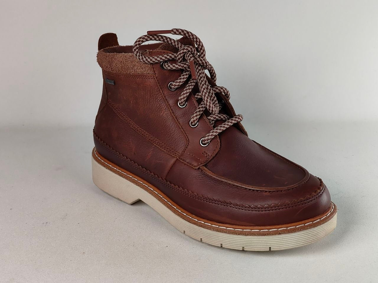 A dark brown leather lace-up ankle boot with a thick cream-colored sole and brown-and-white patterned laces, shown from a three-quarters angle against a neutral light gray background.