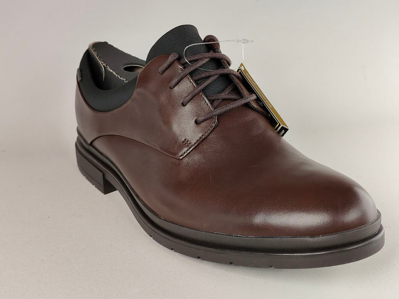 Brown leather dress shoe on a light gray background