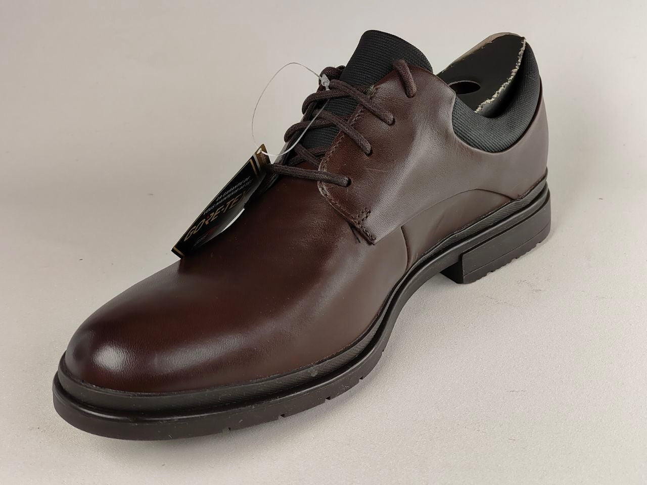 Brown leather dress shoe on a light gray background