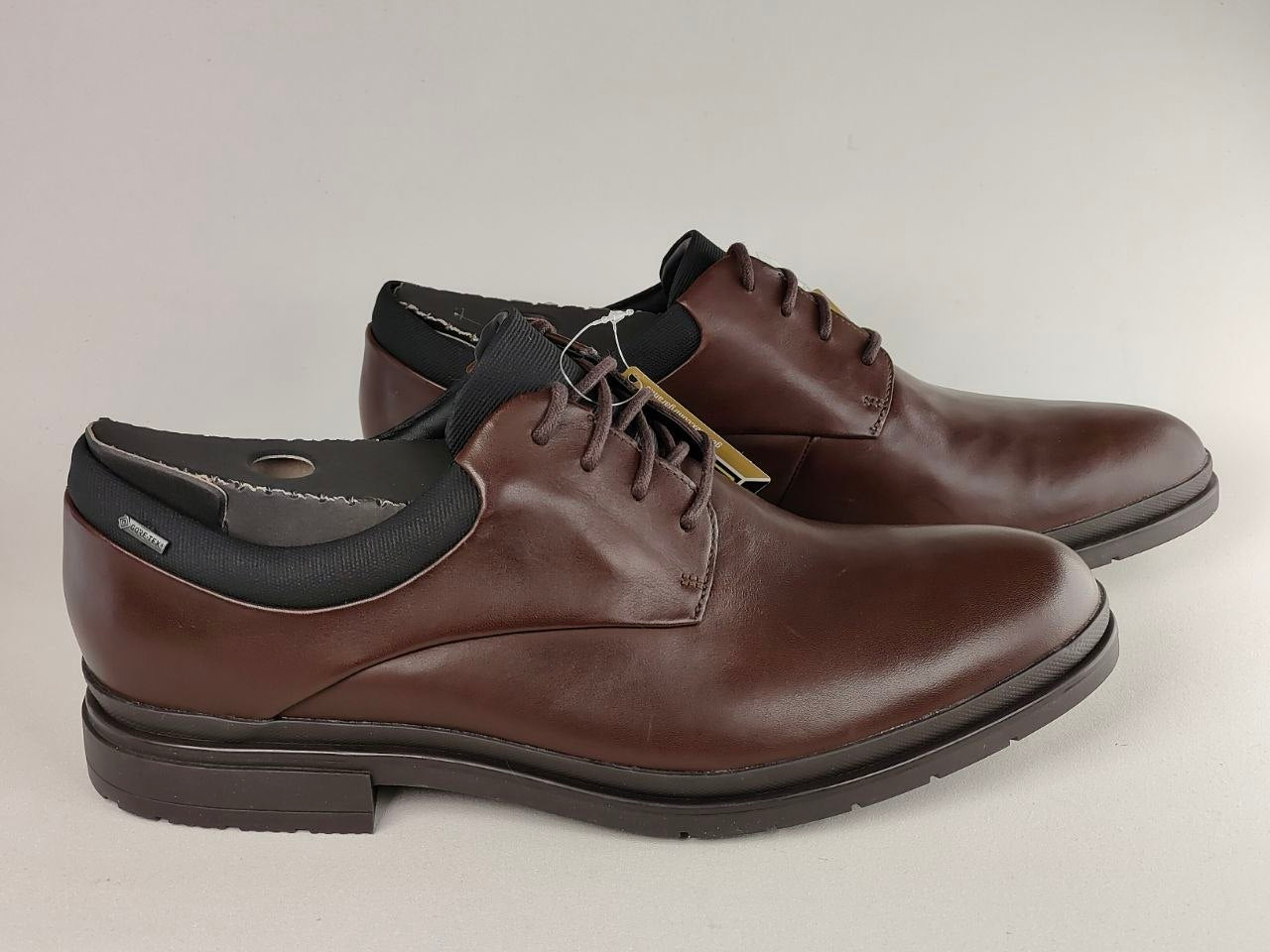 Pair of brown leather shoes with black soles on a light gray background
