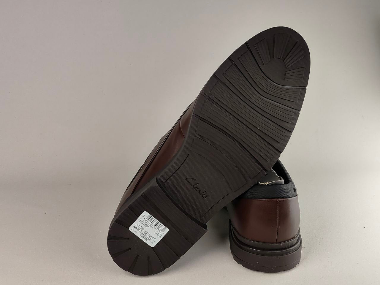 Brown leather shoes with a focus on the sole and brand name on a light gray background