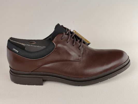 Brown leather shoe with black sole on a light gray background