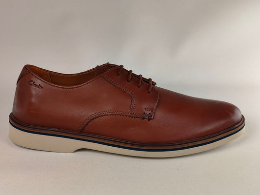 Brown leather shoe with white sole on a light gray background