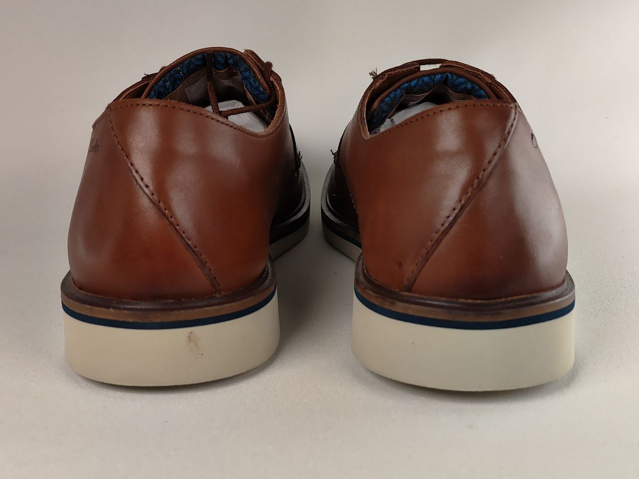 Pair of brown leather shoes with white soles on a light background