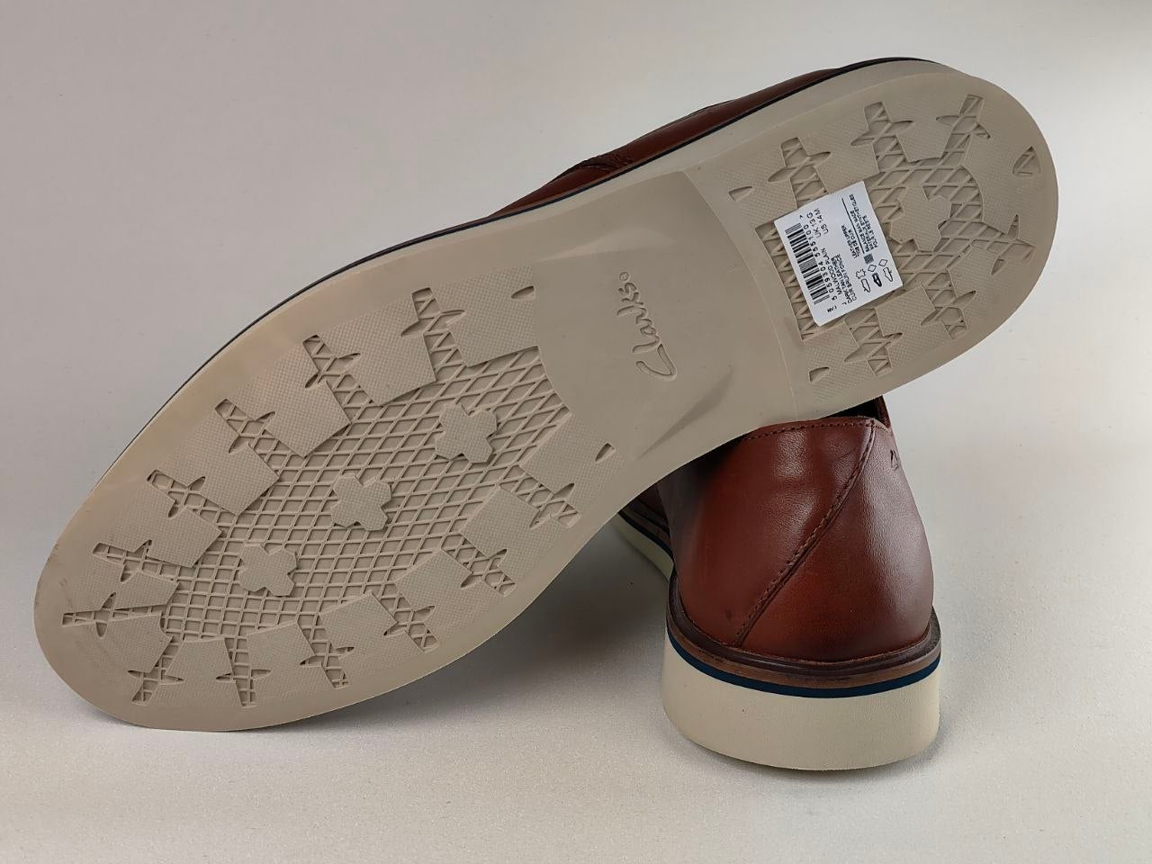 Brown leather shoe with a visible brand label on a light gray background