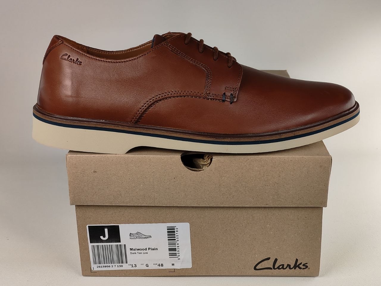 Brown leather shoe on top of a Clarks shoe box with a beige background