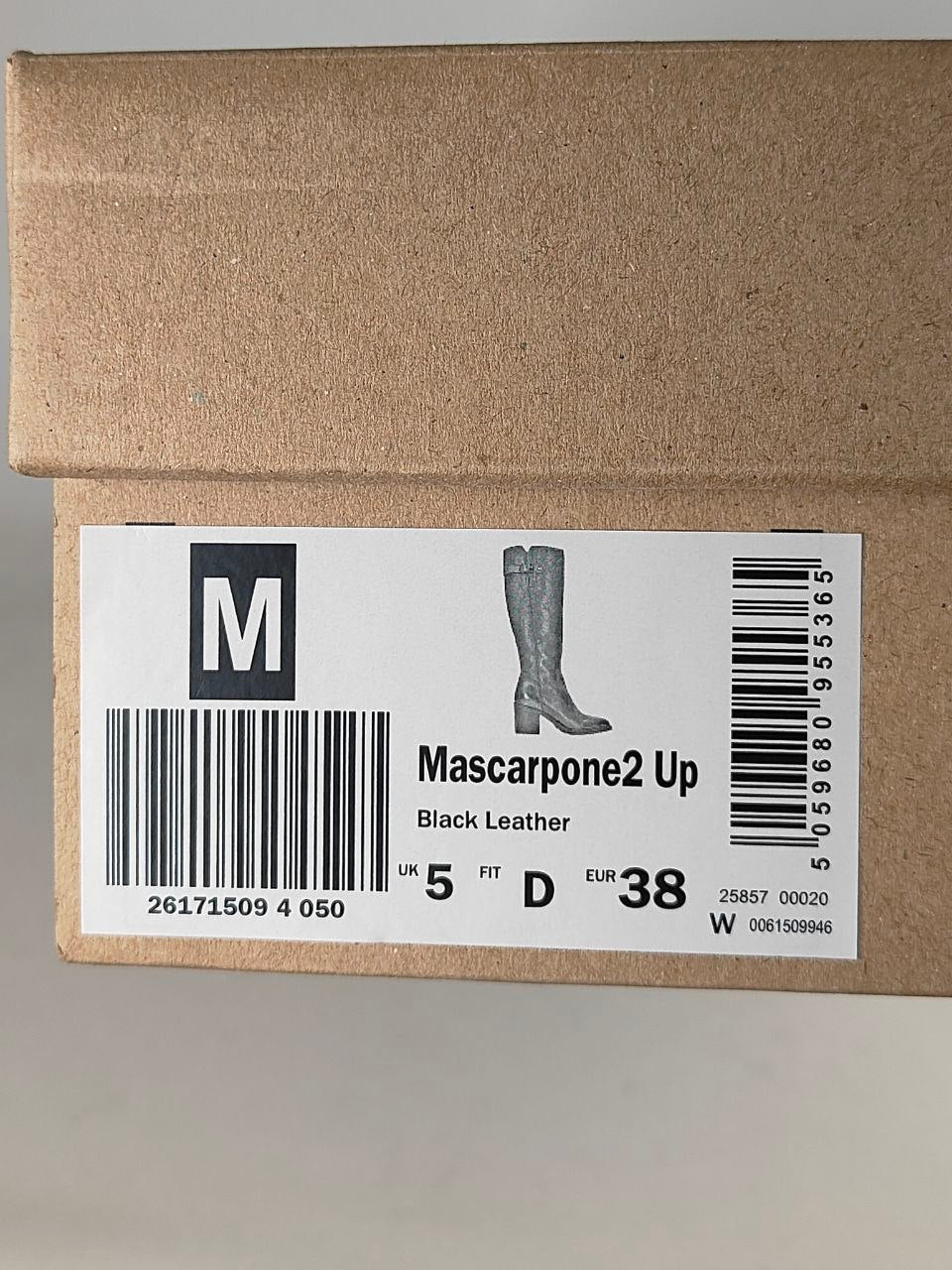 A brown cardboard shoe box with a white size label reading 'M' and 'Mascarpone2 Up Black Leather', showing a boot silhouette and barcode.