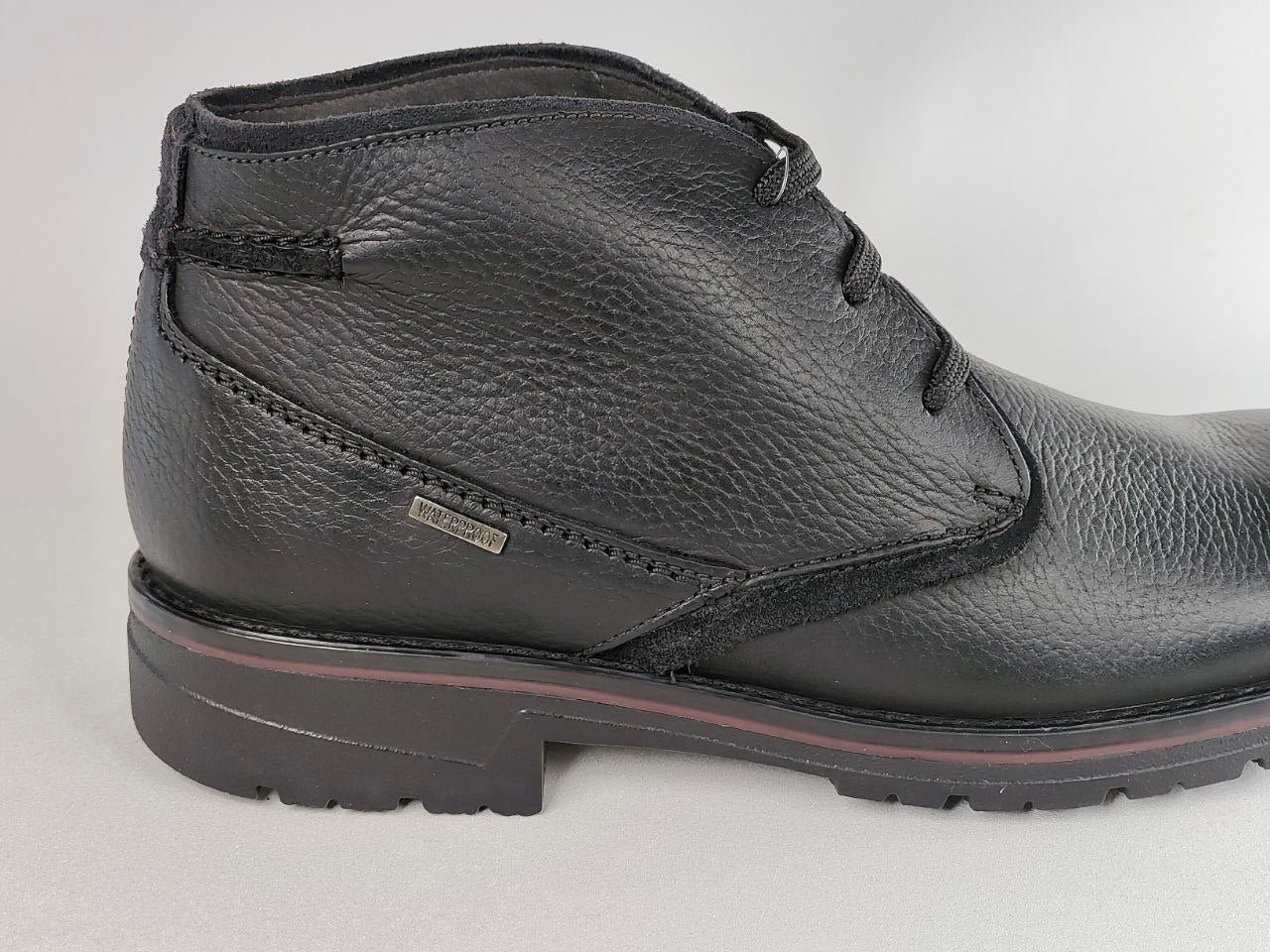 Black leather boot on a light gray background