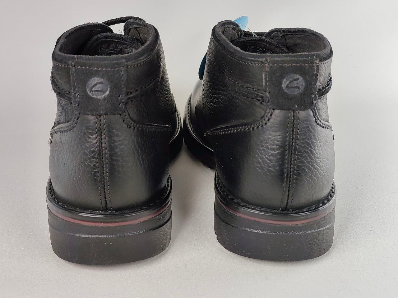 Pair of black leather boots on a light gray background