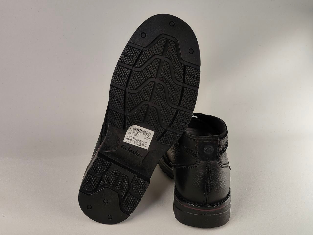 Black leather boots with soles facing up on a gray background