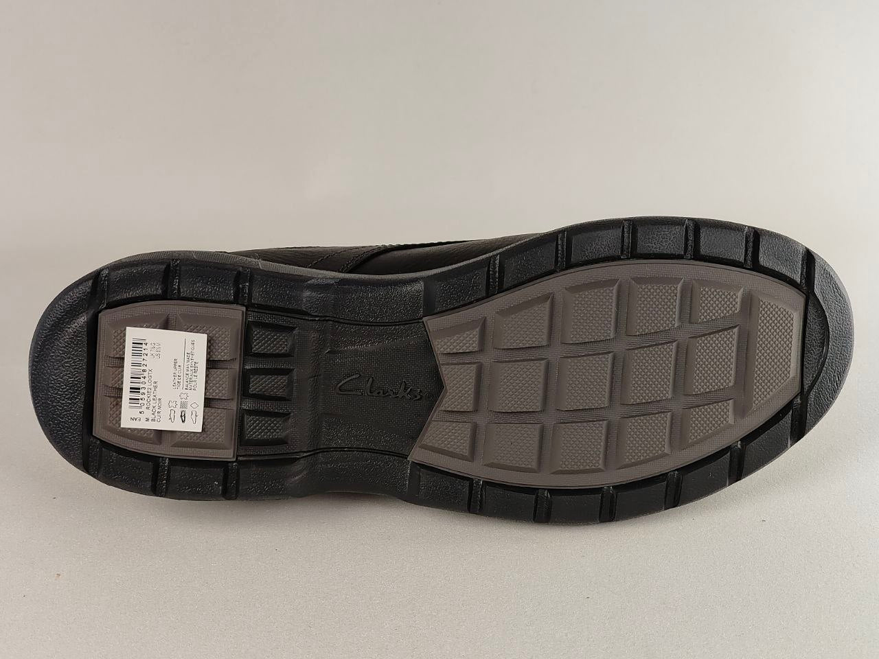 Black shoe sole with tread pattern and a brand label on a light gray background