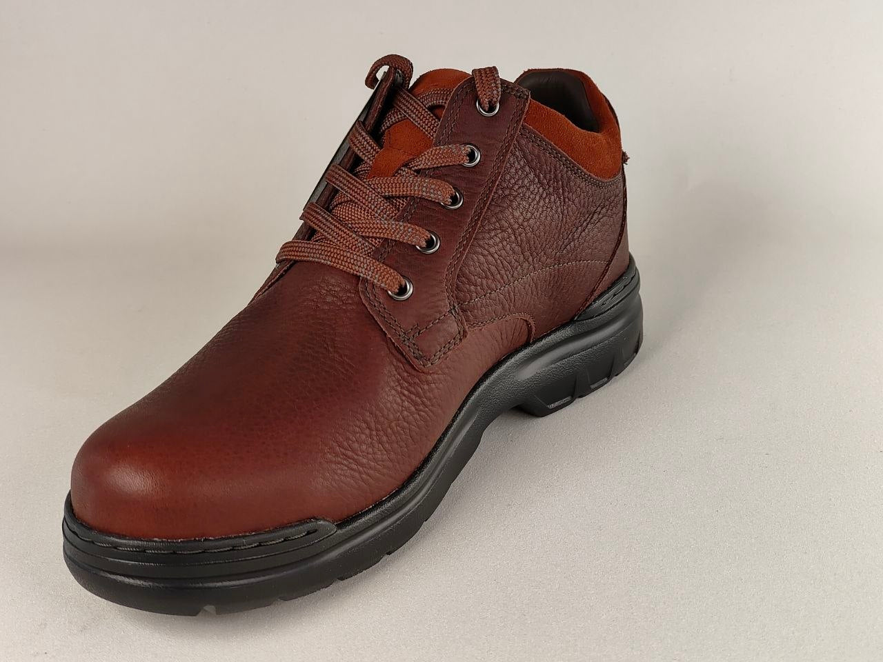Brown leather boot with black sole on a light gray background