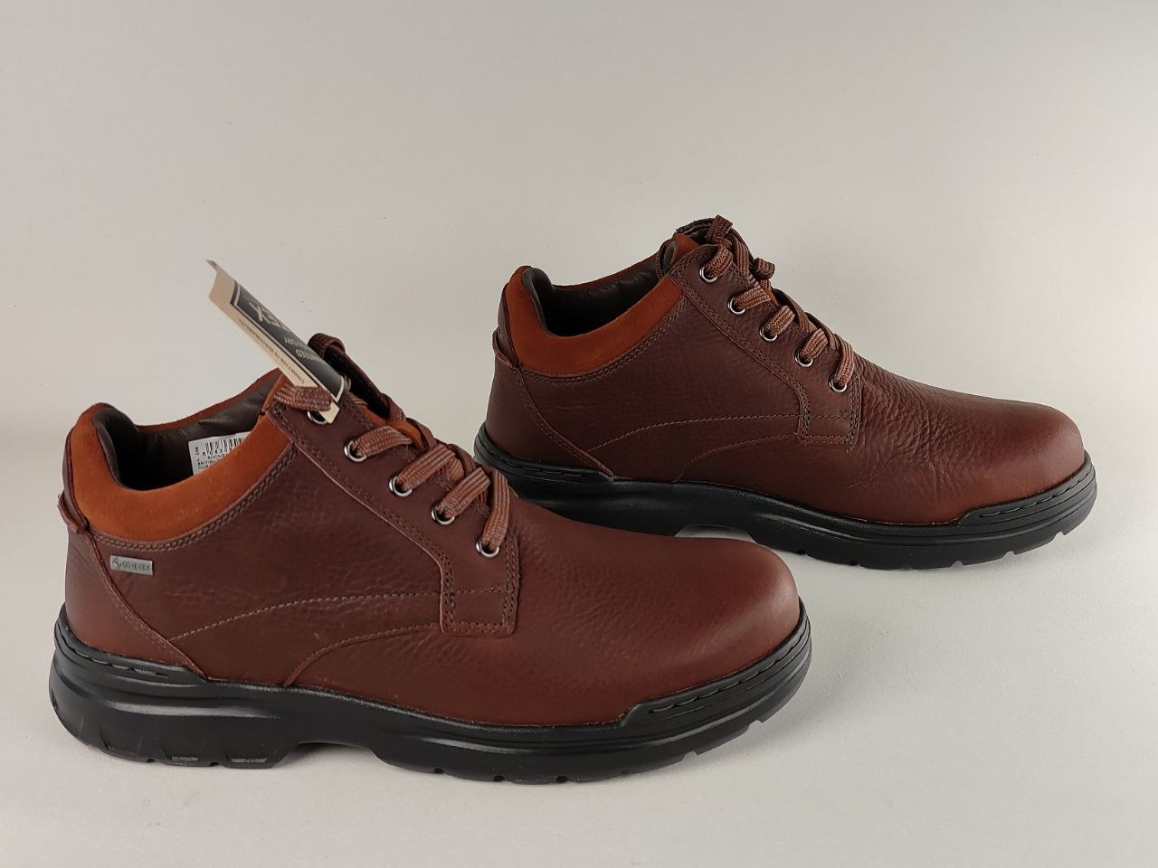 Pair of brown leather shoes with black soles on a light gray background