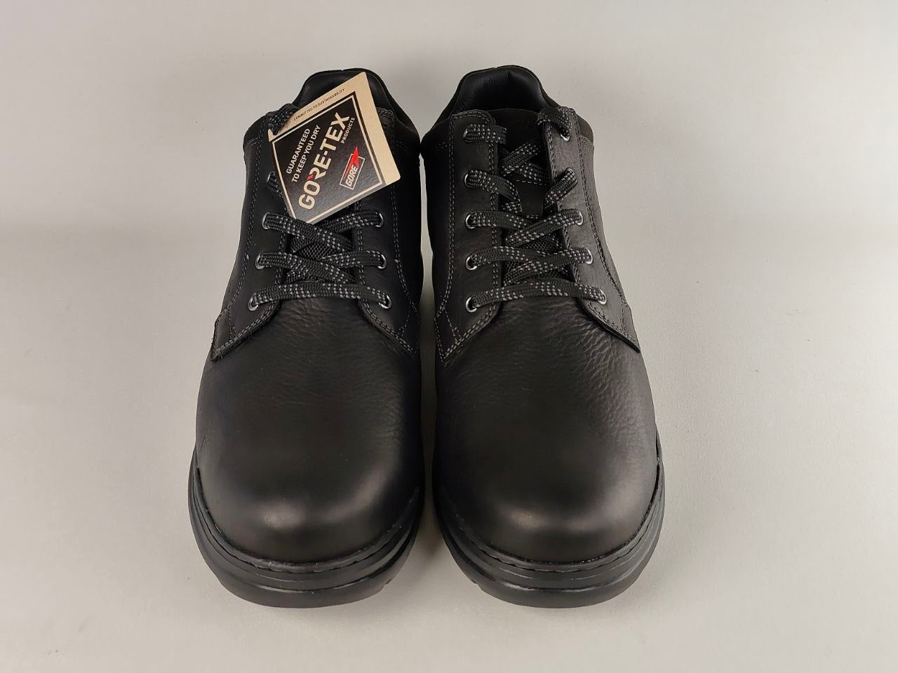 Pair of black leather shoes with GORE-TEX label on a gray background