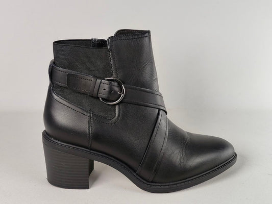 A black leather ankle boot with a block heel, featuring a decorative strap across the instep with a silver-tone buckle, set against a neutral light gray background.