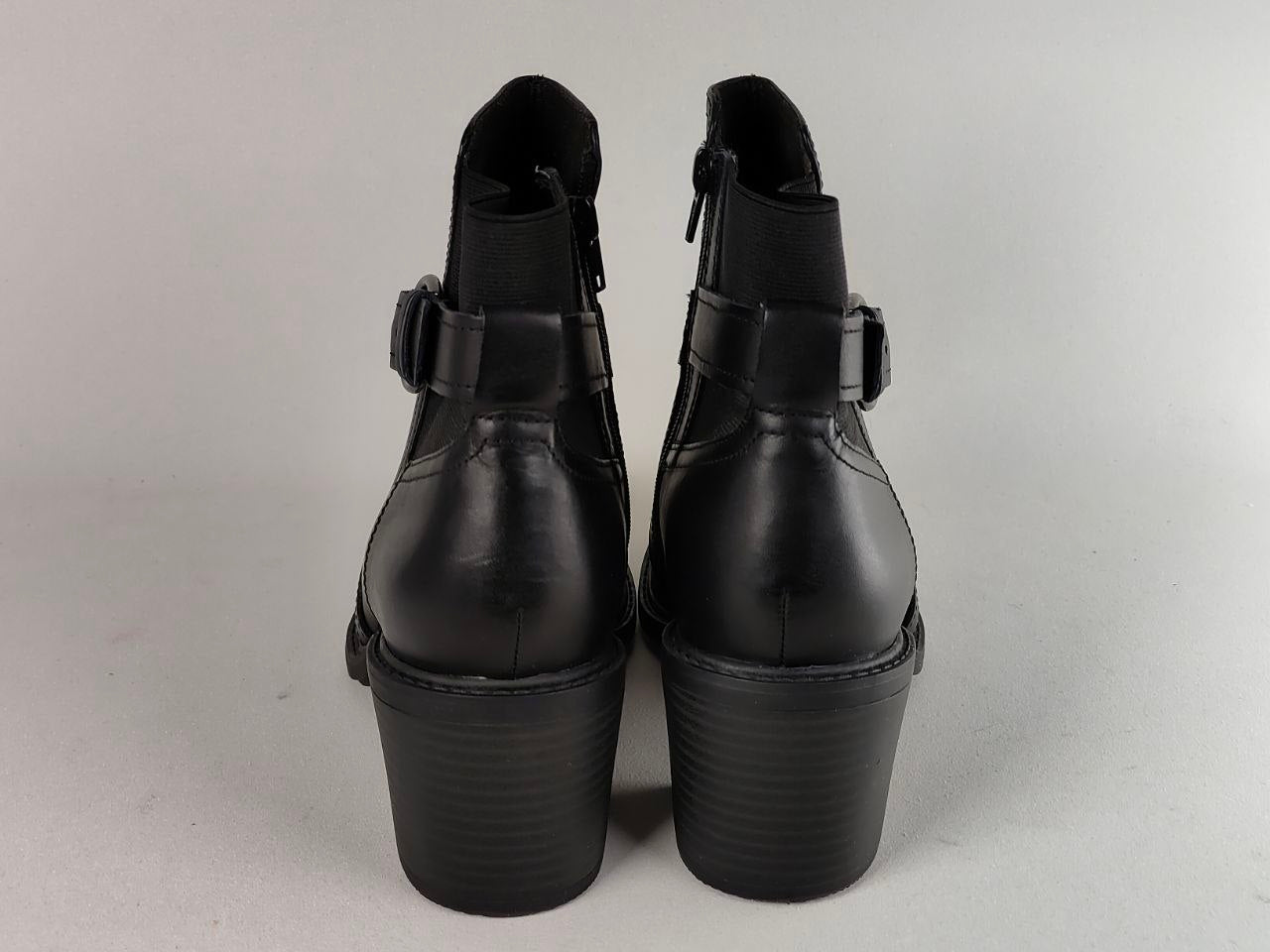 A pair of black leather ankle boots with platform heels and side buckle straps, shown from the back against a light gray background.