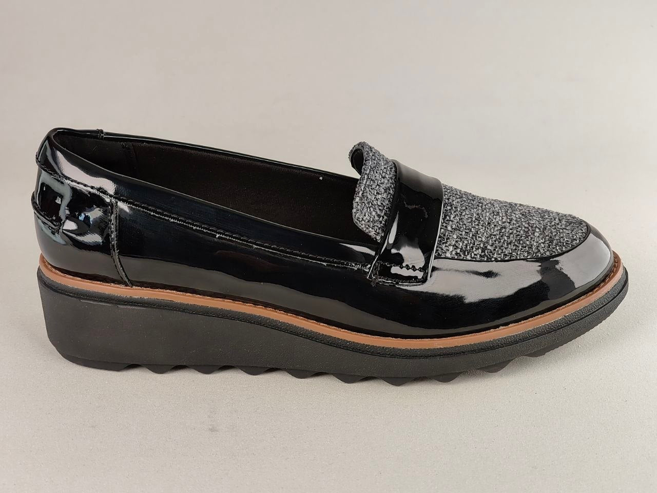 Black patent leather loafer with a platform sole on a light gray background