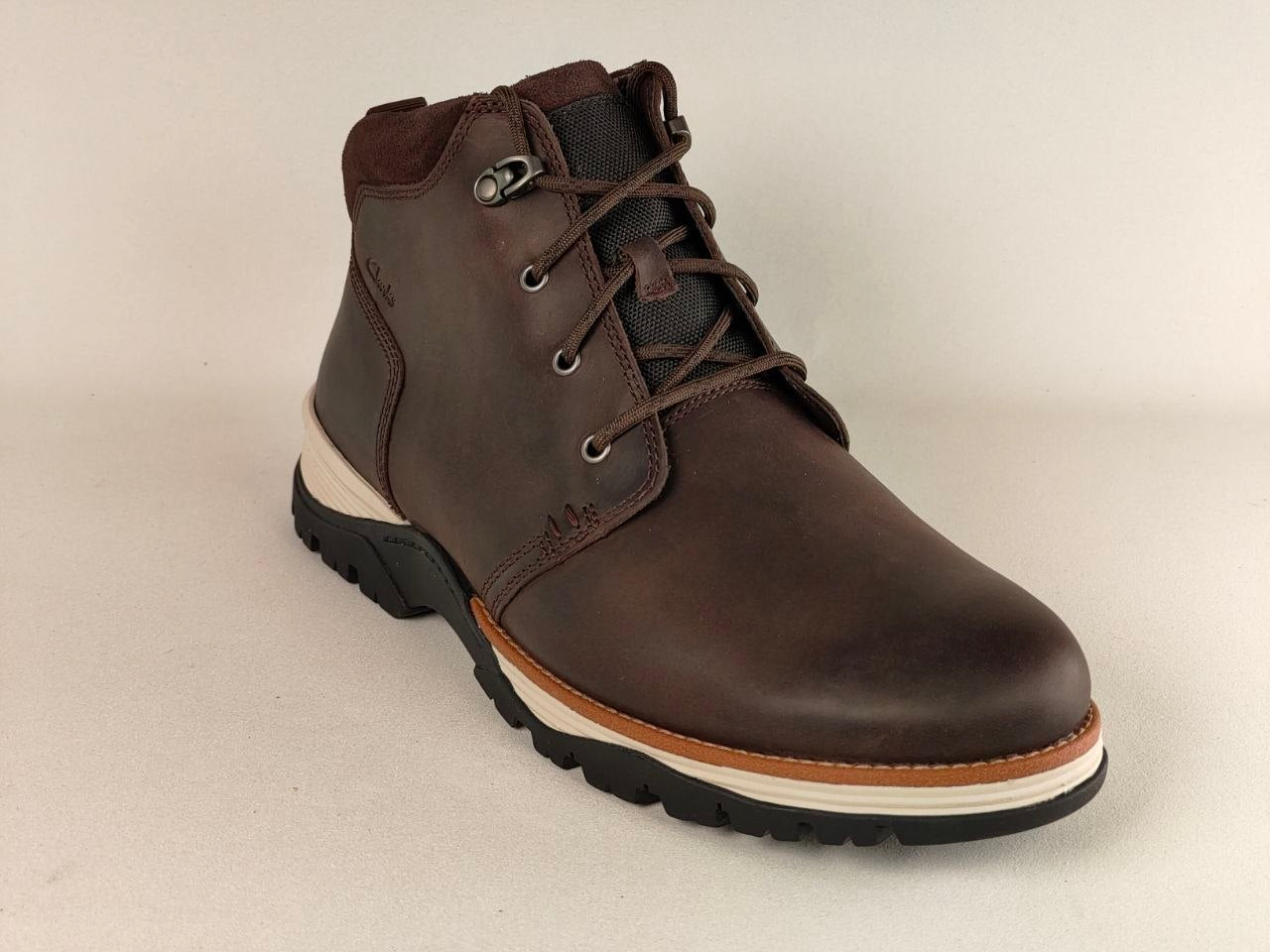 Brown leather boot with a white sole on a beige background