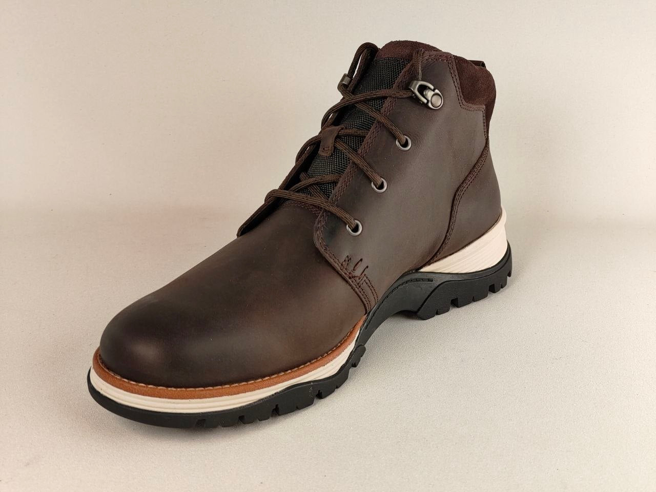 Brown leather boot with a white sole on a beige background