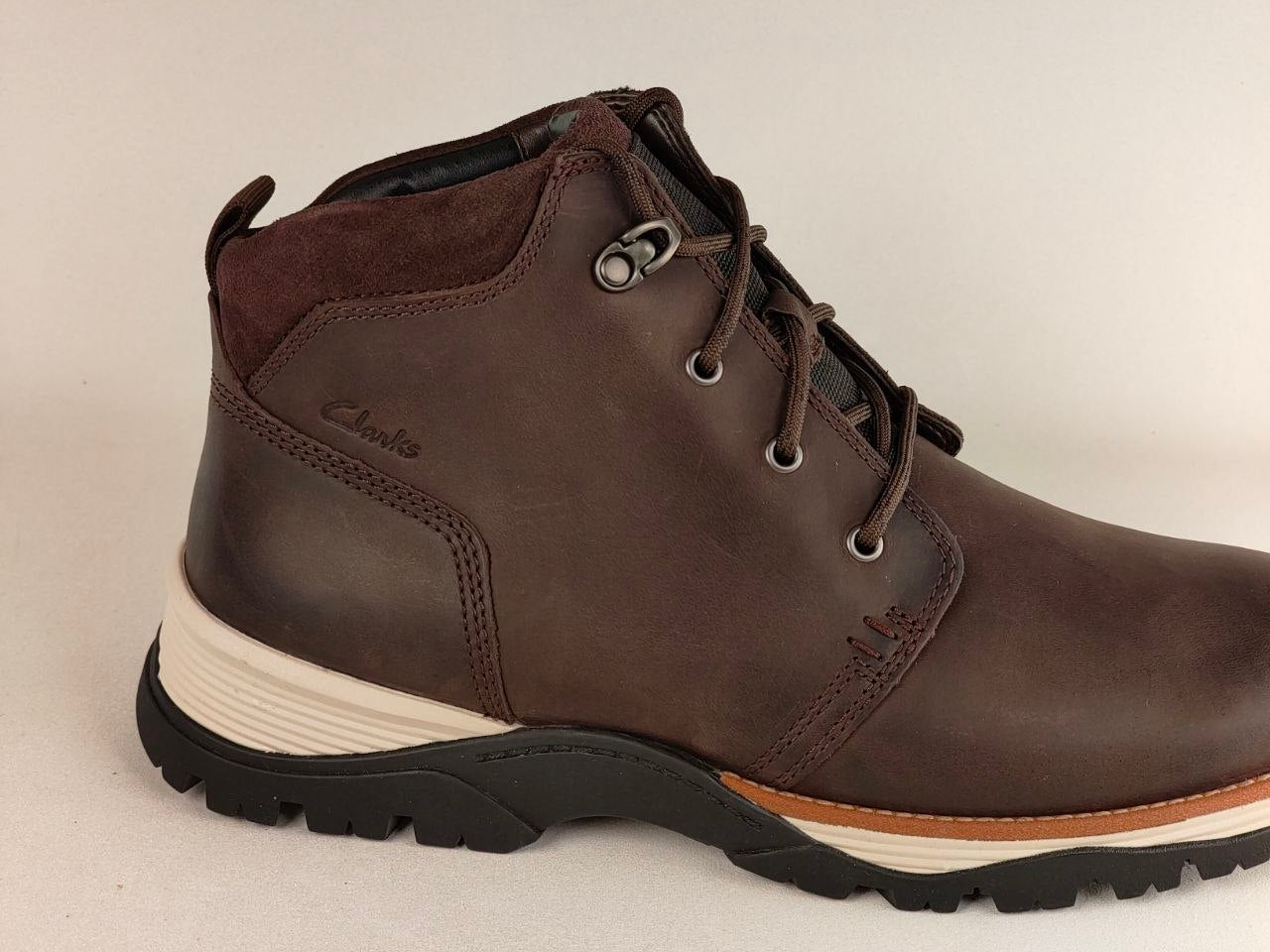 Brown leather boot with a white sole on a beige background