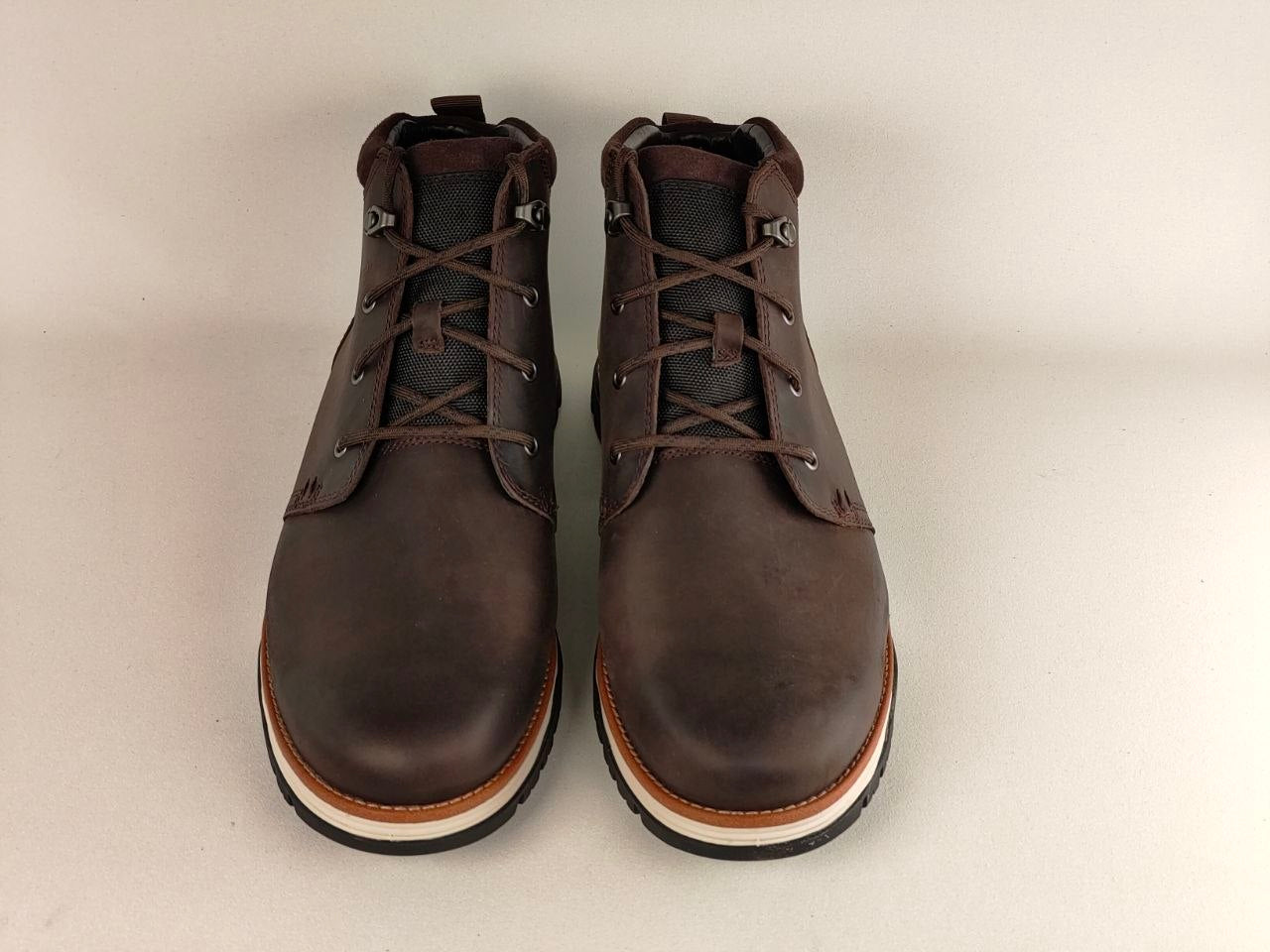 Pair of brown leather boots on a light beige background