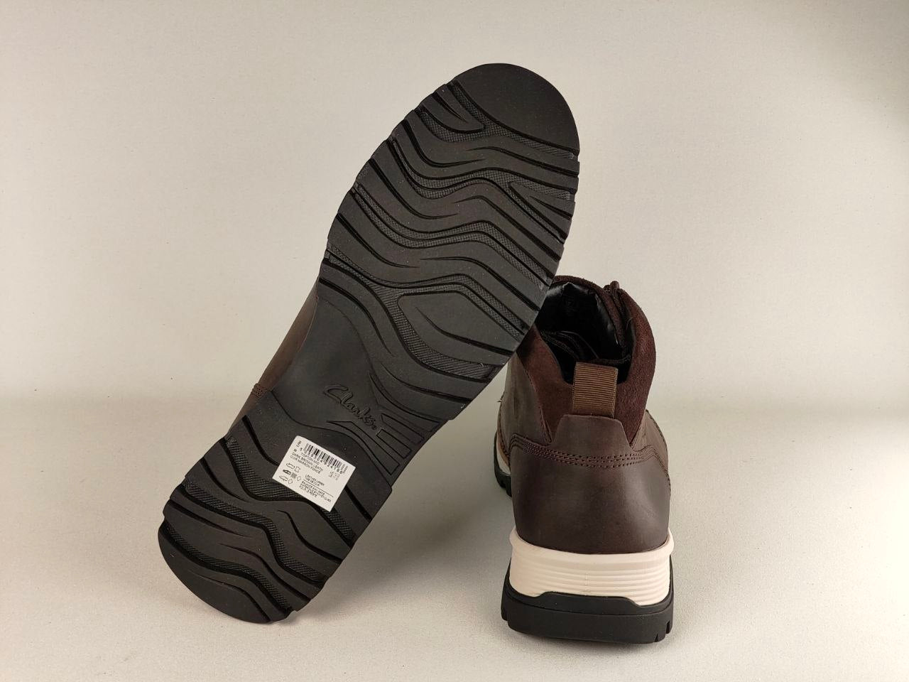 Brown leather boot with a focus on the sole and brand label on a beige background