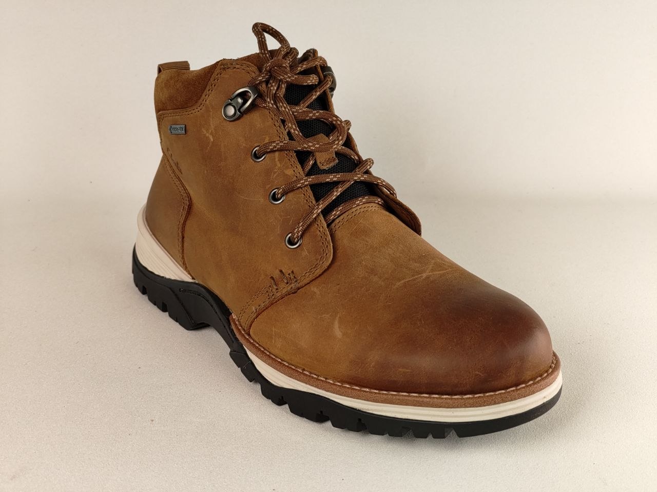 Brown leather boot with laces on a beige background