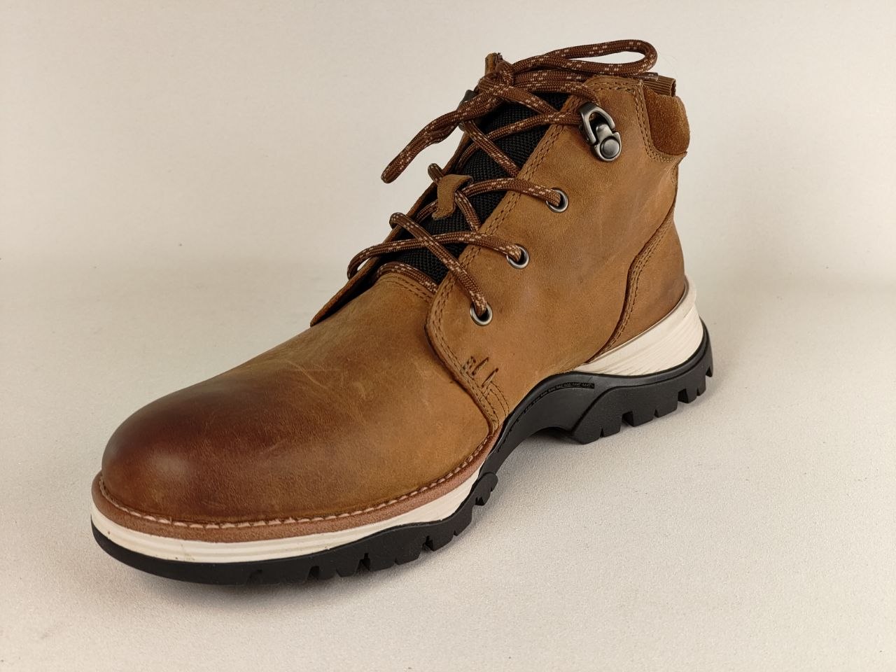 Brown leather boot with a white sole on a beige background