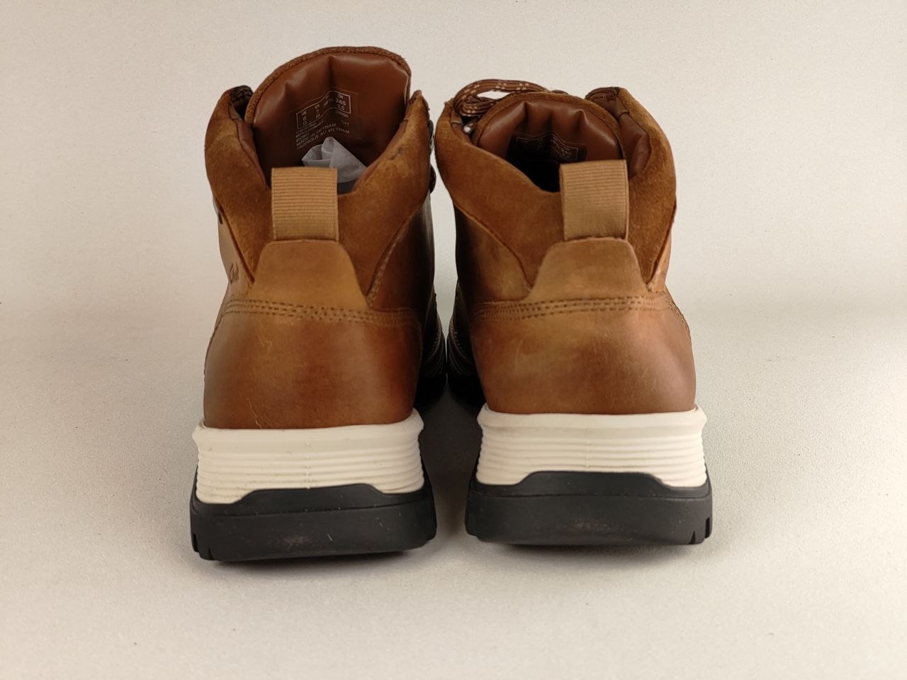 Pair of brown leather boots with white soles on a beige background