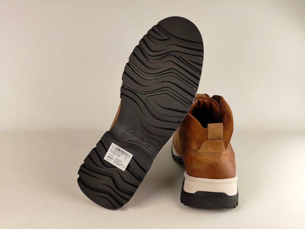Brown leather boot with black sole on a beige background