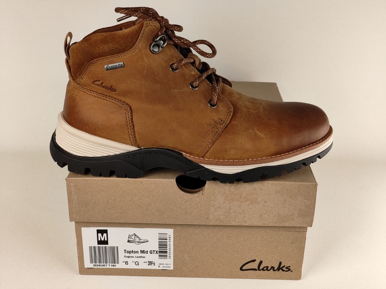 Brown leather boot on a Clarks shoe box with a beige background