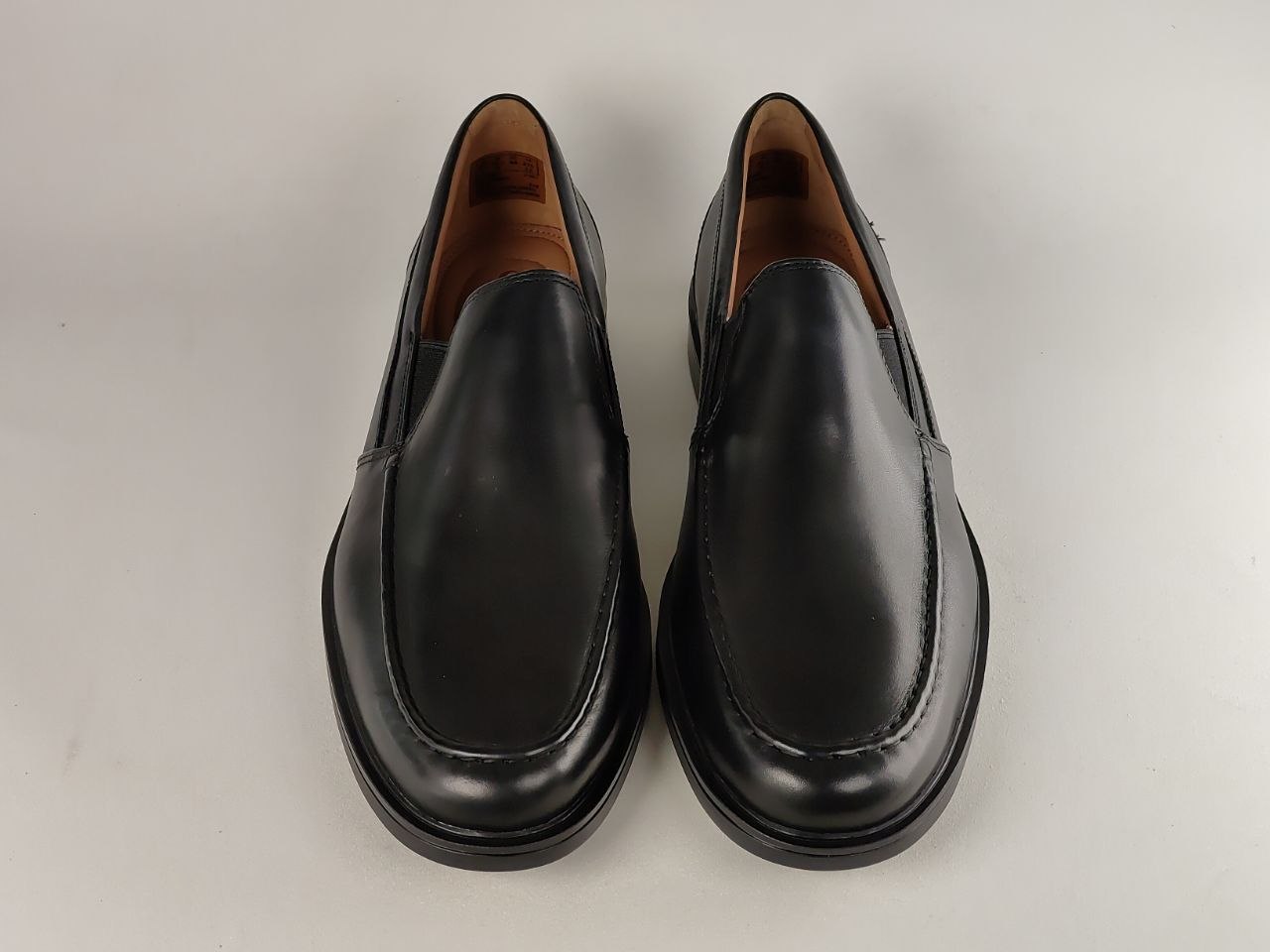Pair of black leather loafers on a light gray background