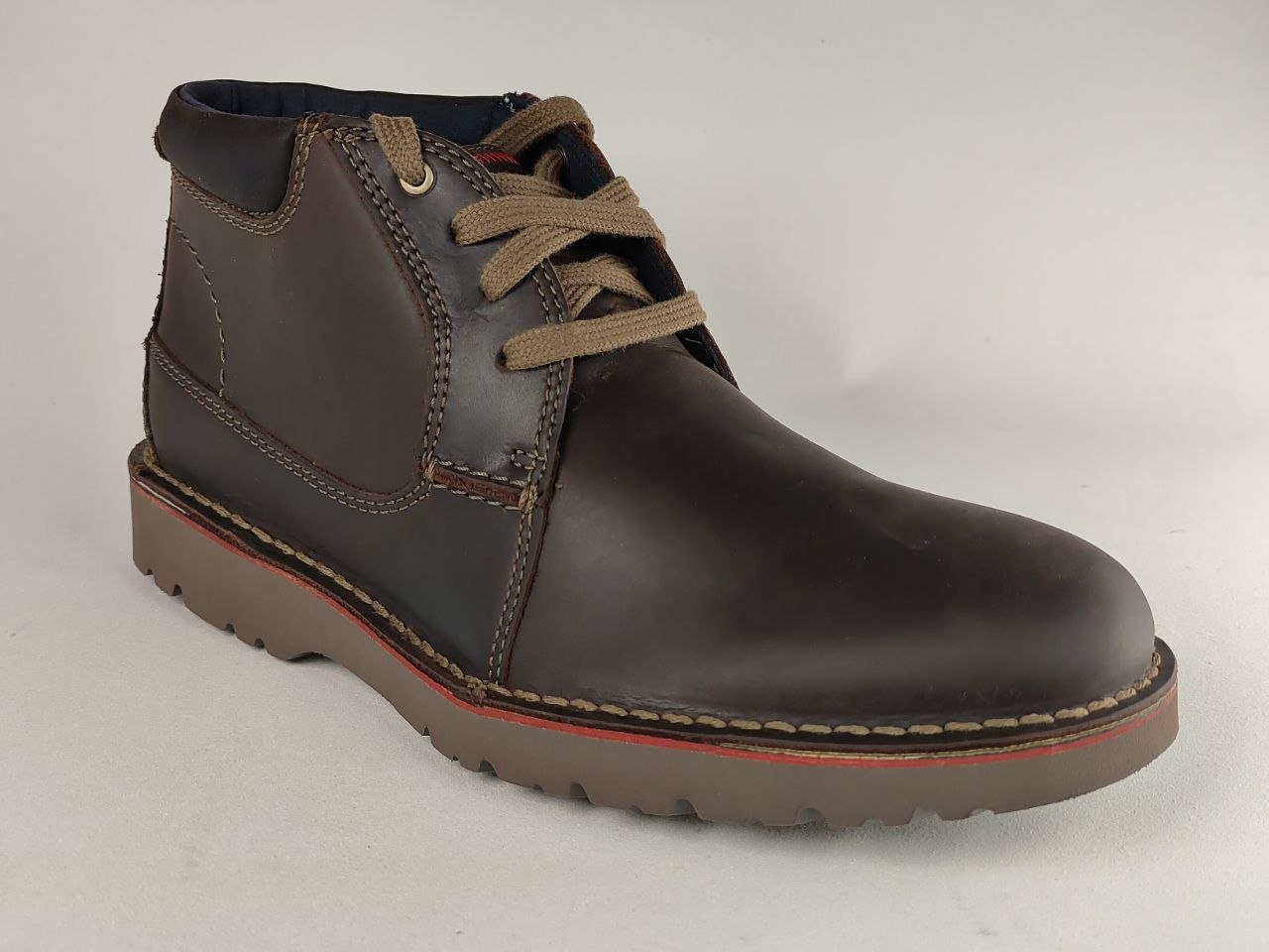 Brown leather boot with brown laces on a light gray background